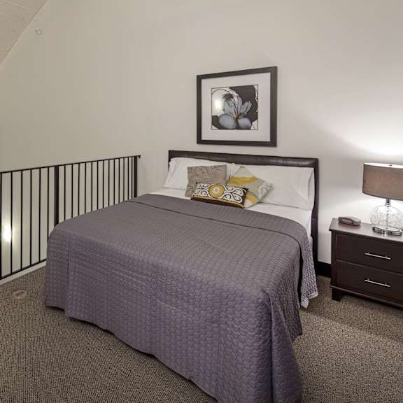 a bedroom with a bed, nightstand, and a picture on the wall.