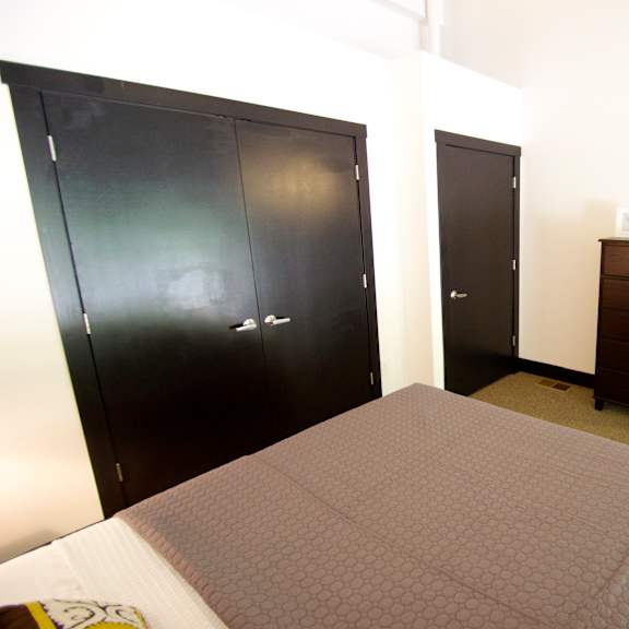 a bedroom with a bed, dresser, and two closets.