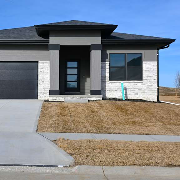 a modern house with a grey garage door and a black roof.