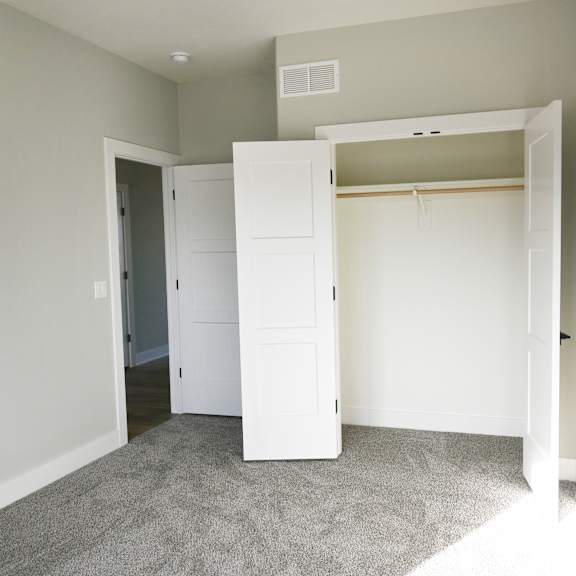 a room with a white closet and carpeted floor.