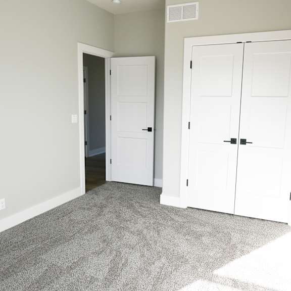 a room with a carpeted floor and two white doors.