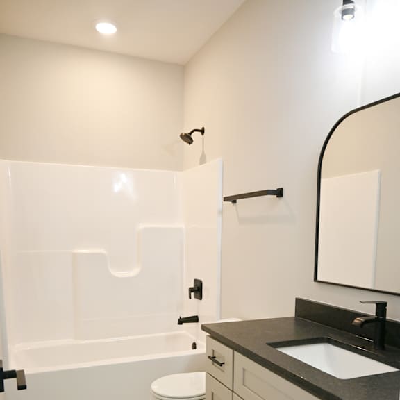 a white toilet sits in a bathroom with a black counter top.