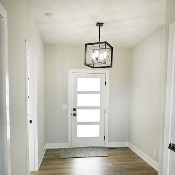 a hallway with a light hanging from the ceiling and a door at the end.