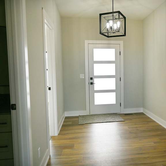a hallway with a light hanging from the ceiling and a white door.