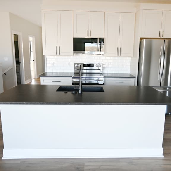 a kitchen with a black countertop and stainless steel appliances.
