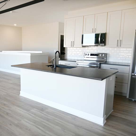 a modern kitchen with a large island and a ceiling fan.