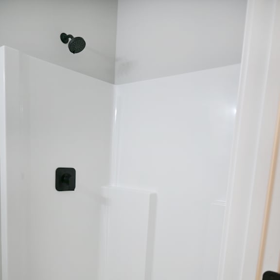 a white shower stall with a drain in the middle.