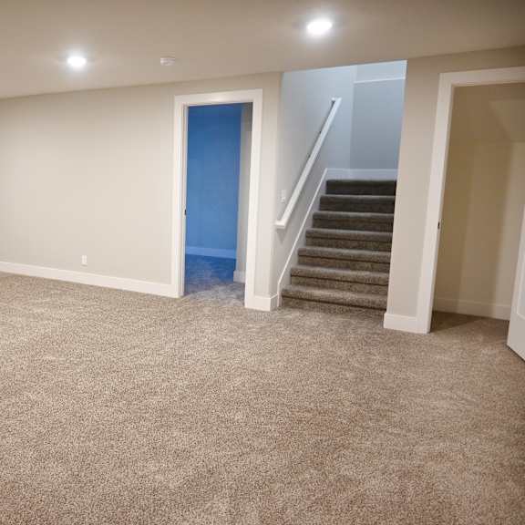 a room with a carpeted floor and a staircase.
