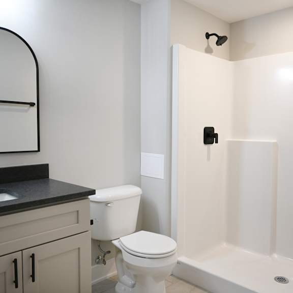 a white toilet sits in a bathroom next to a sink and a shower.