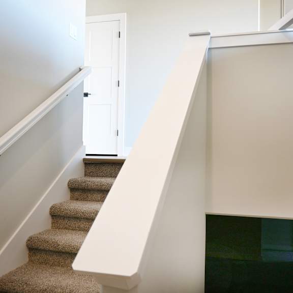 a staircase with a carpeted runner and white handrail.
