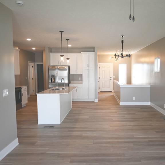 a modern kitchen with a white island and wooden floors.