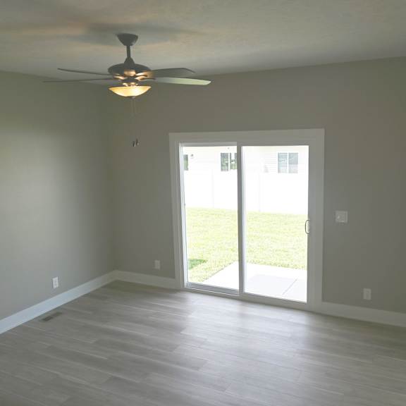 a room with a ceiling fan and sliding glass doors.