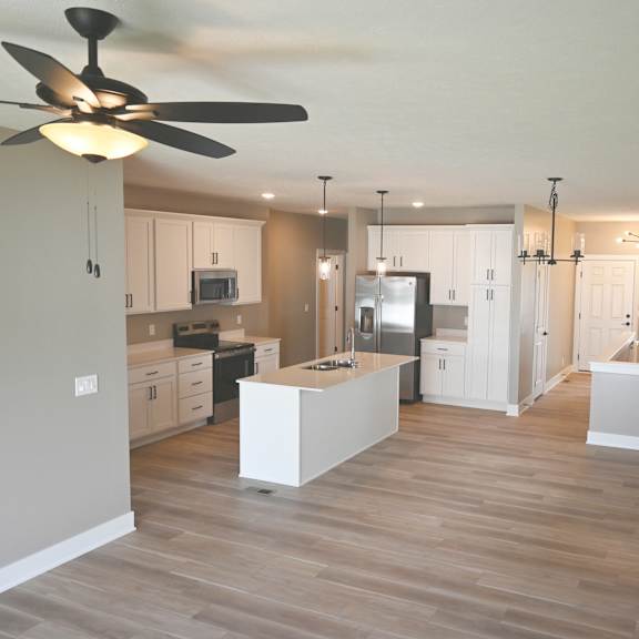 a kitchen with a fan on the ceiling and wooden floors.