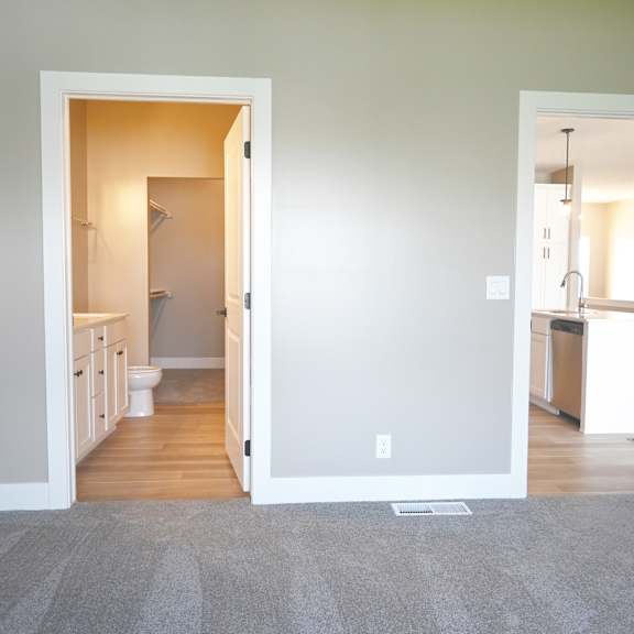 a room with a carpeted floor and two open doors leading to other rooms.