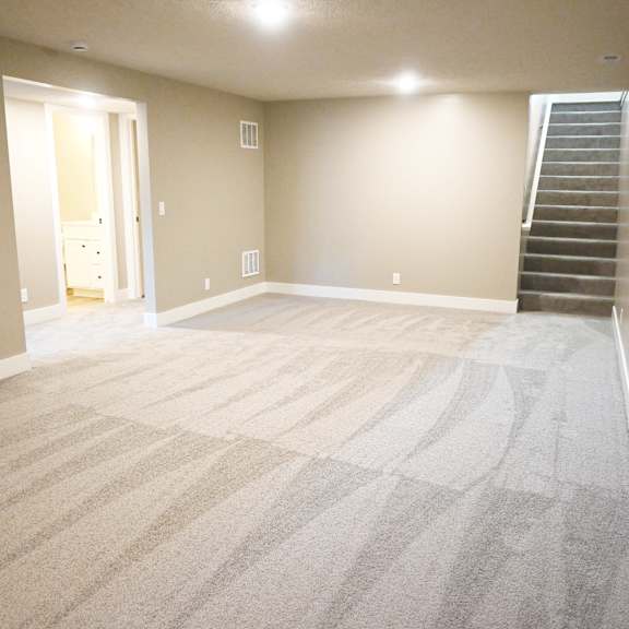 a room with a carpeted floor and a staircase on the right side.