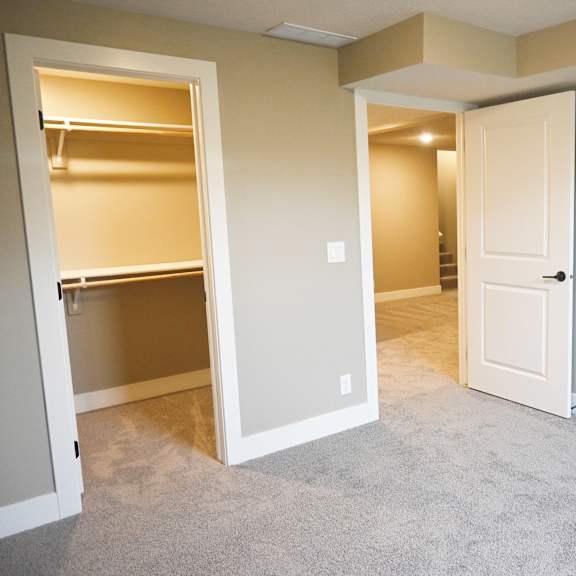 a room with a white door and a white closet with shelves.