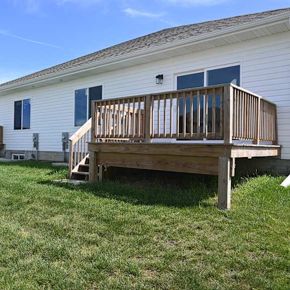 a white house with a wooden deck in front.