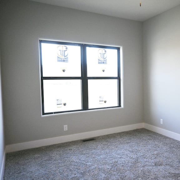 a room with a carpeted floor and a window with blinds.