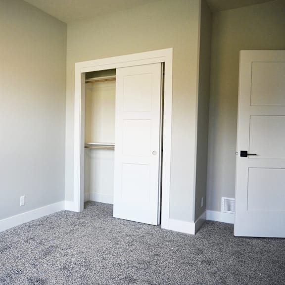 a room with a carpeted floor and two white doors.