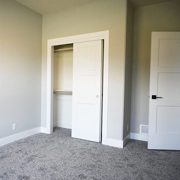 a room with a carpeted floor and two white doors.