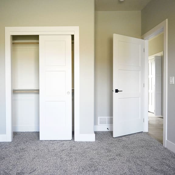 a room with a carpeted floor and two white doors.