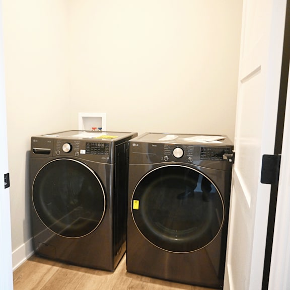 two black front loading washing machines in a laundry room.