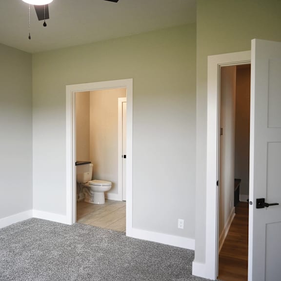 a room with a toilet in the middle and a doorway leading to another room.