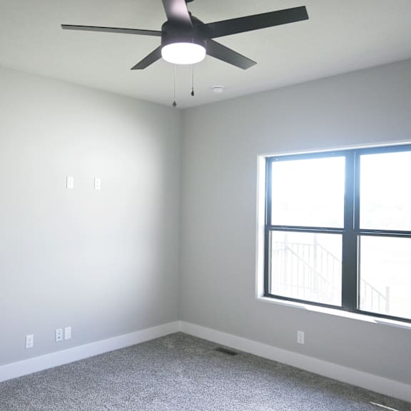 a room with a ceiling fan and a window.