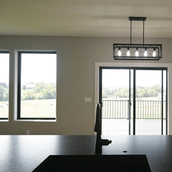 a room with a black table and a view of a parking lot through a glass door.