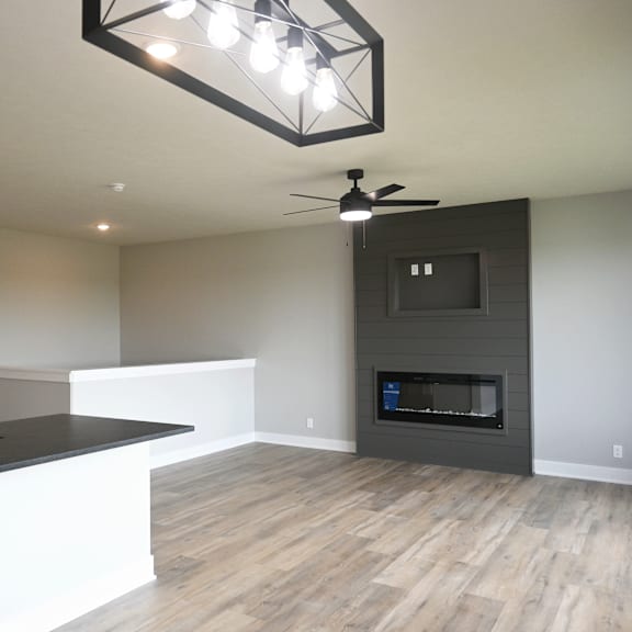 a modern kitchen with a black countertop and a fireplace in the living room.