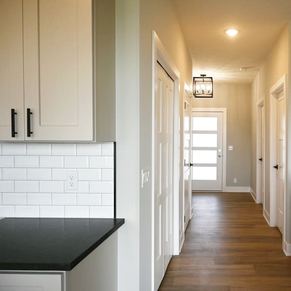 a long hallway with white walls and wood floors.