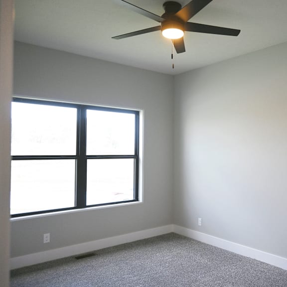 a room with a ceiling fan and a window.