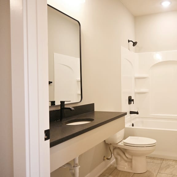 a white toilet is in a bathroom with a black counter top.