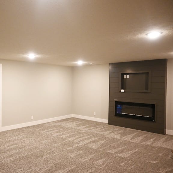 a spacious living room with a fireplace and a staircase.