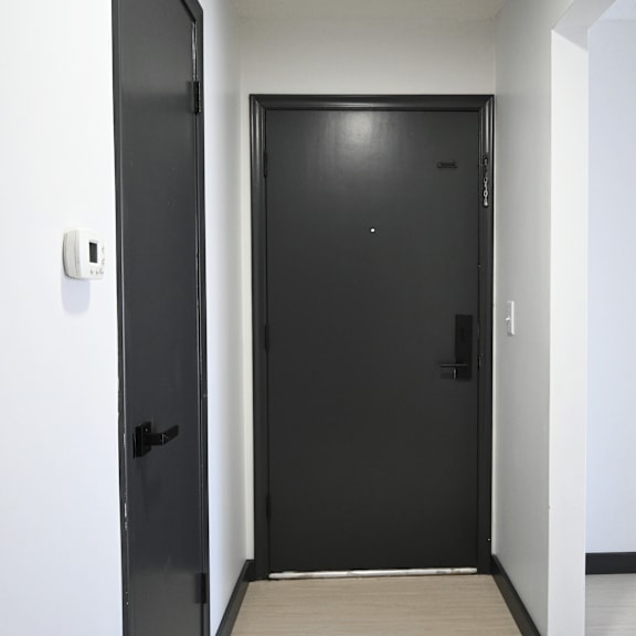 a black door with a handle and a lock is in a white room.