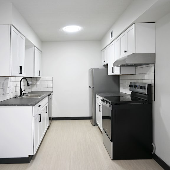 a kitchen with white cabinets and black appliances.