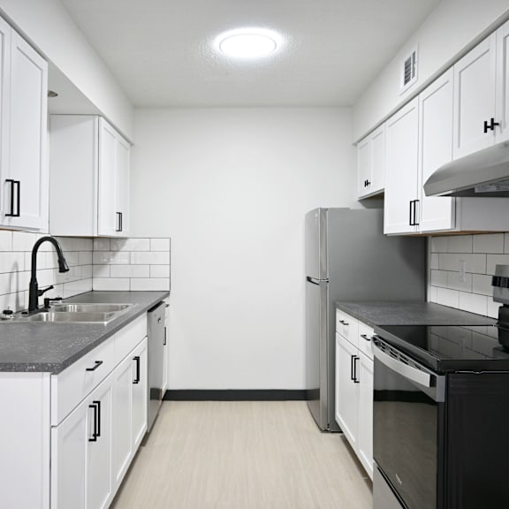 a kitchen with black countertops and white cabinets.