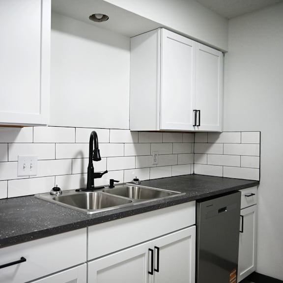 a kitchen with white cabinets and a black countertop.