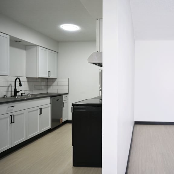 a kitchen with white cabinets and black appliances.