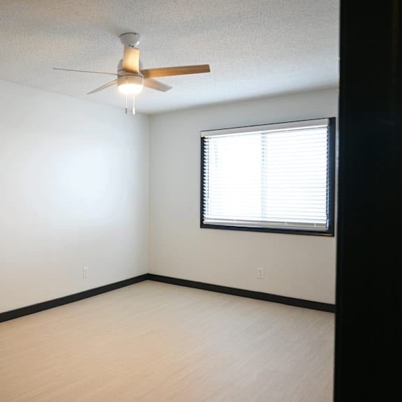a room with a ceiling fan and a window with blinds.