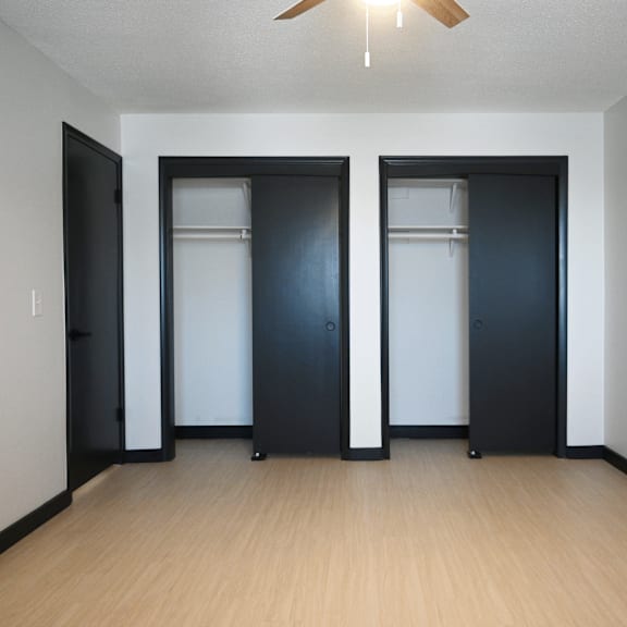 a room with two black doors and a ceiling fan.