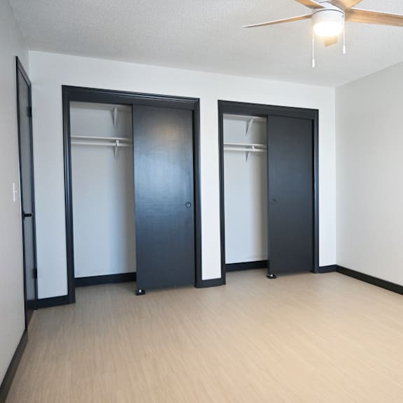 a room with a ceiling fan and three doors.