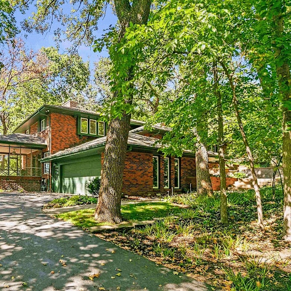 a house with a driveway and trees surrounding it.