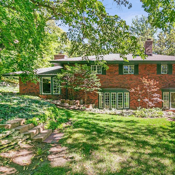 a red brick house with a green lawn in front.