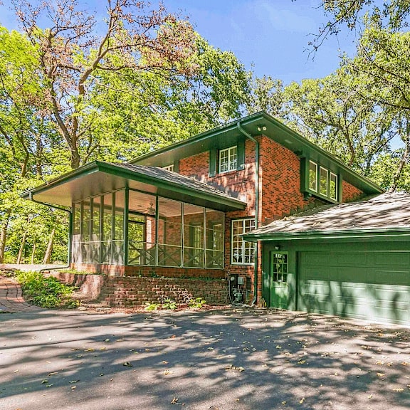 a house with a green garage door is surrounded by trees.