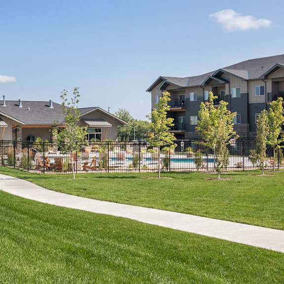 a grassy area in front of a building with a pool.
