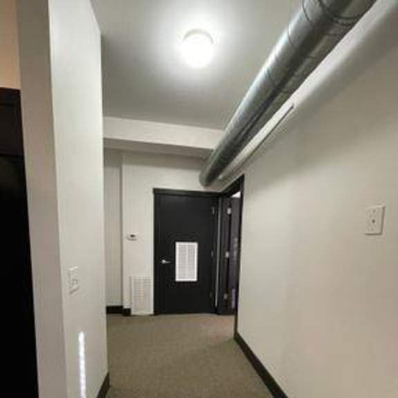 a hallway with a black door and a white wall.