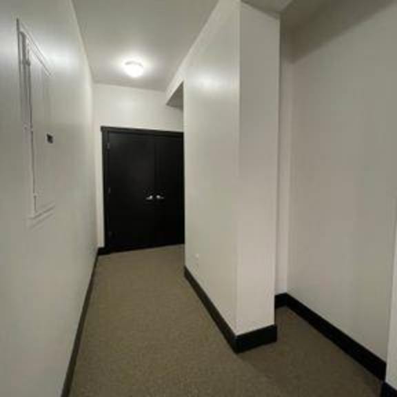 a long hallway with a black door at the end.