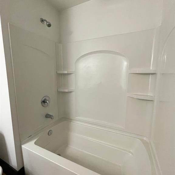 a white bathroom with a tub and shower.