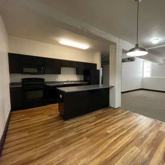 a room with wooden flooring and a black countertop.